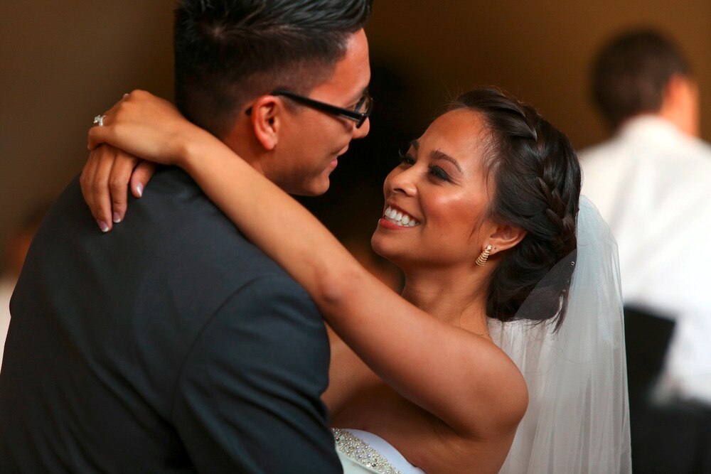Asian bride dancing while looking happily at groom.