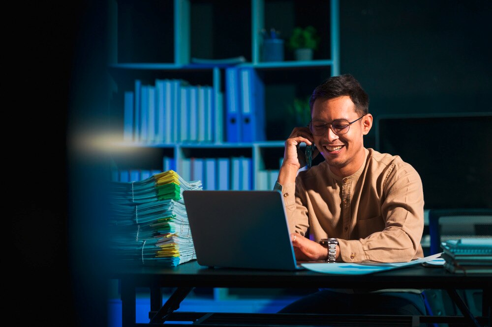 Asian man working overtime in a dark office.