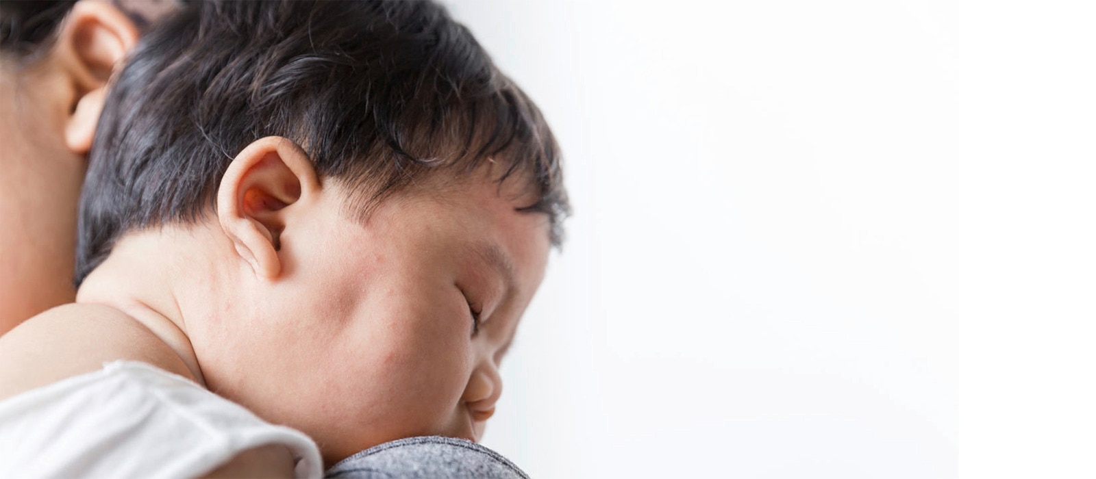 seorang bayi sedang tertidur di pundak ibunya