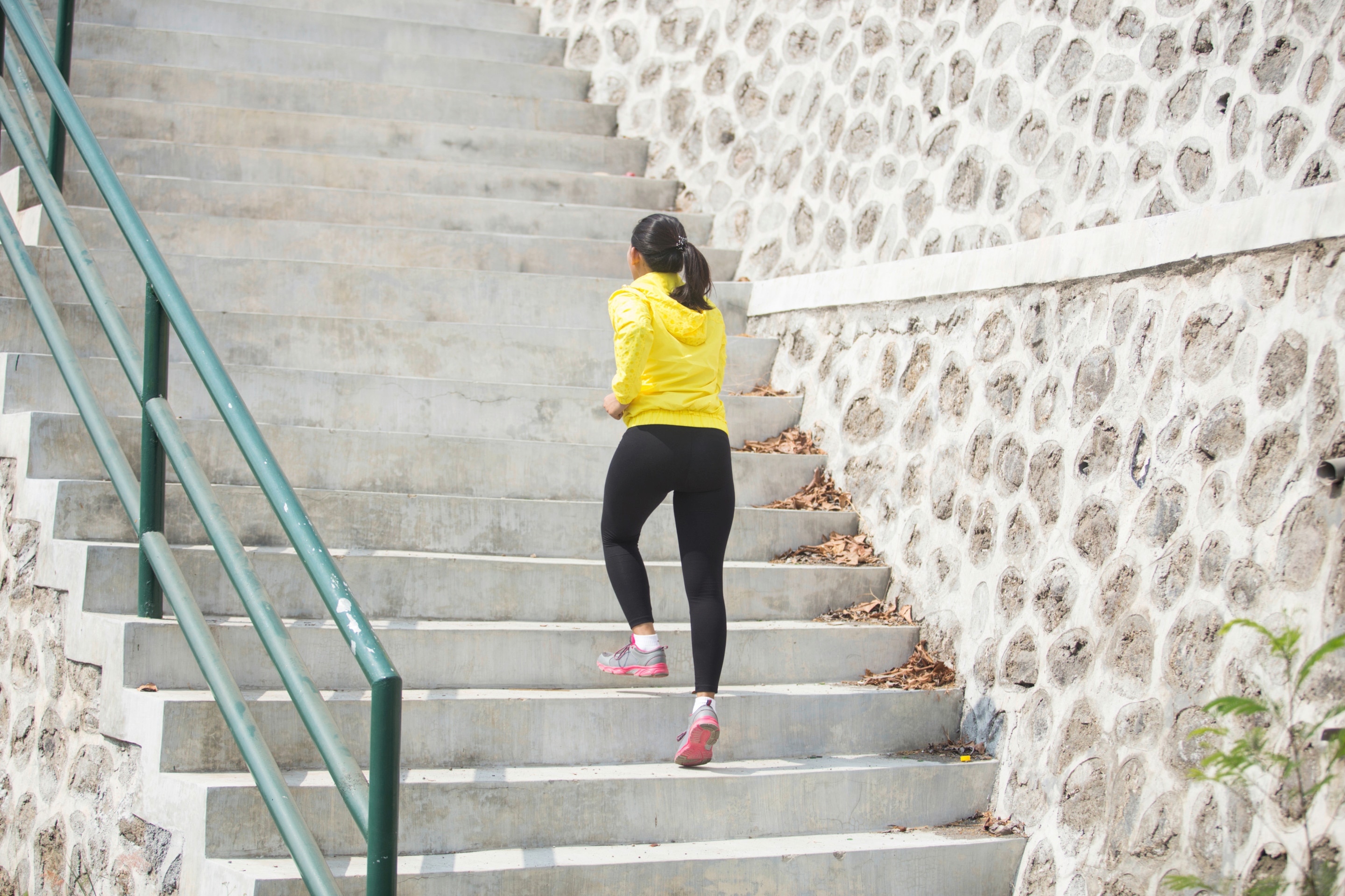 Woman in yellow jacket climbing up the stairs.