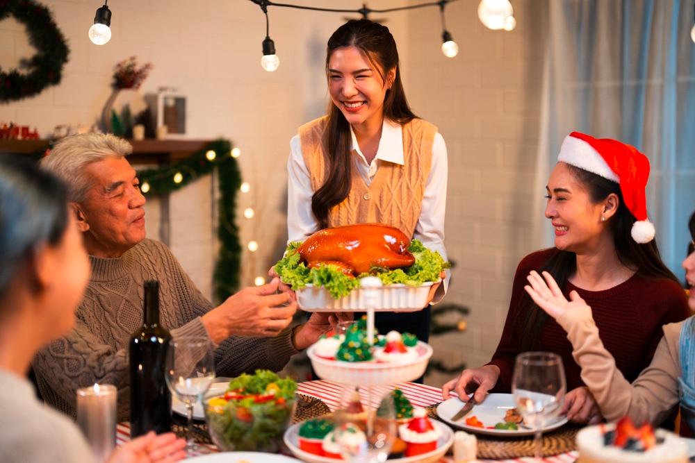 Asian woman serving food at a Christmas party.