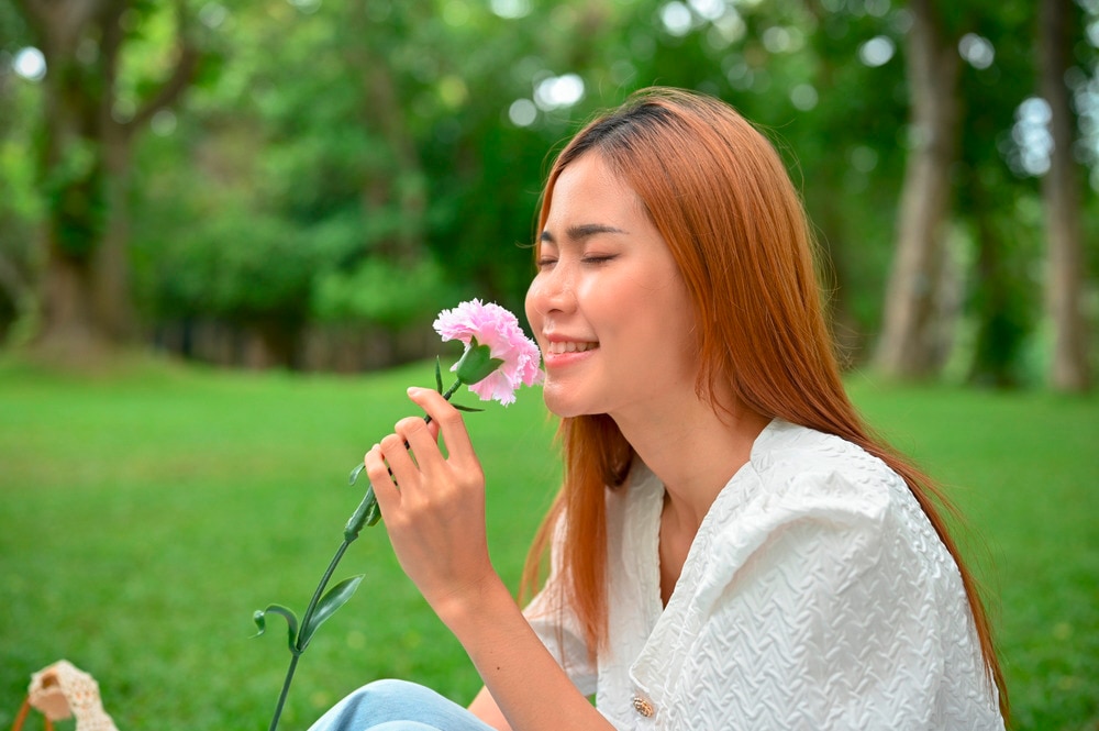 Woman smelling a flower at the park.