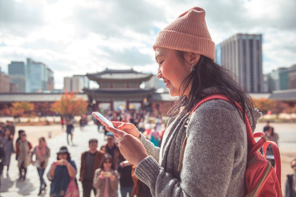 Asian woman texting at Gyeongbokgung Palace in Korea.