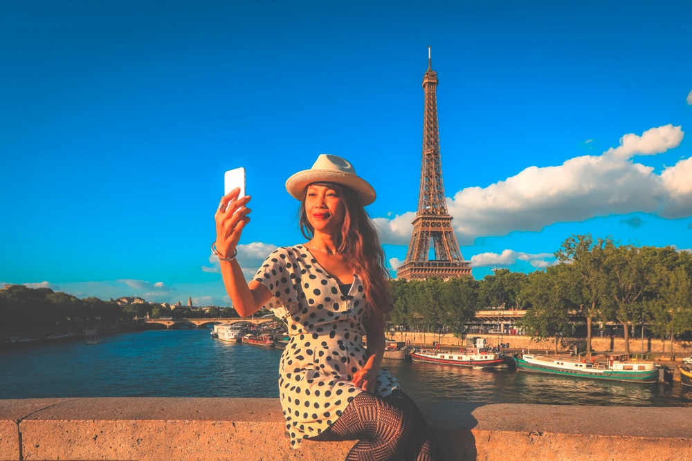 Asian woman taking a selfie with the Eiffel Tower.