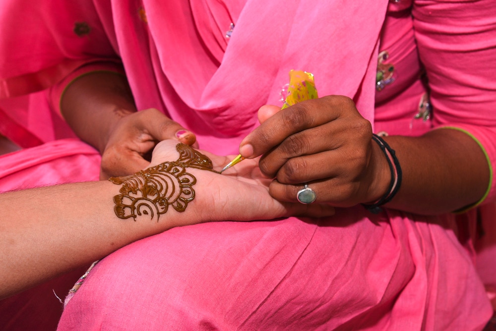 Closeup of a woman’s hand getting henna body art.