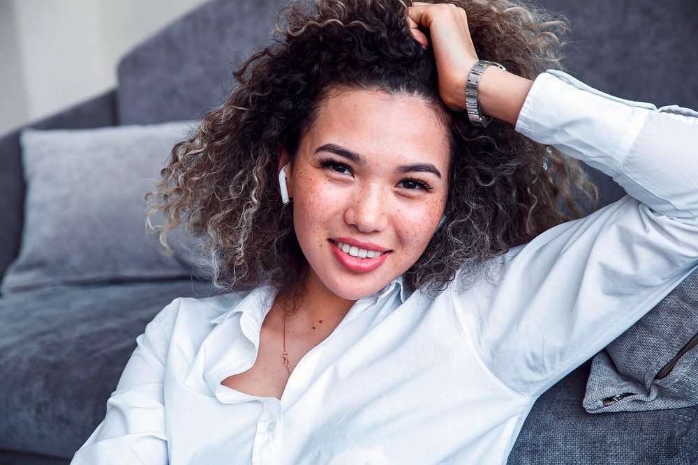A portrait of smiling woman with curly hair in white dress shirt.