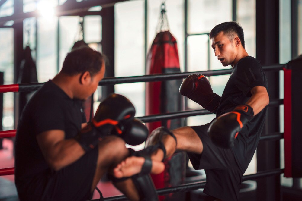 Man kicking his opponent while training boxing.