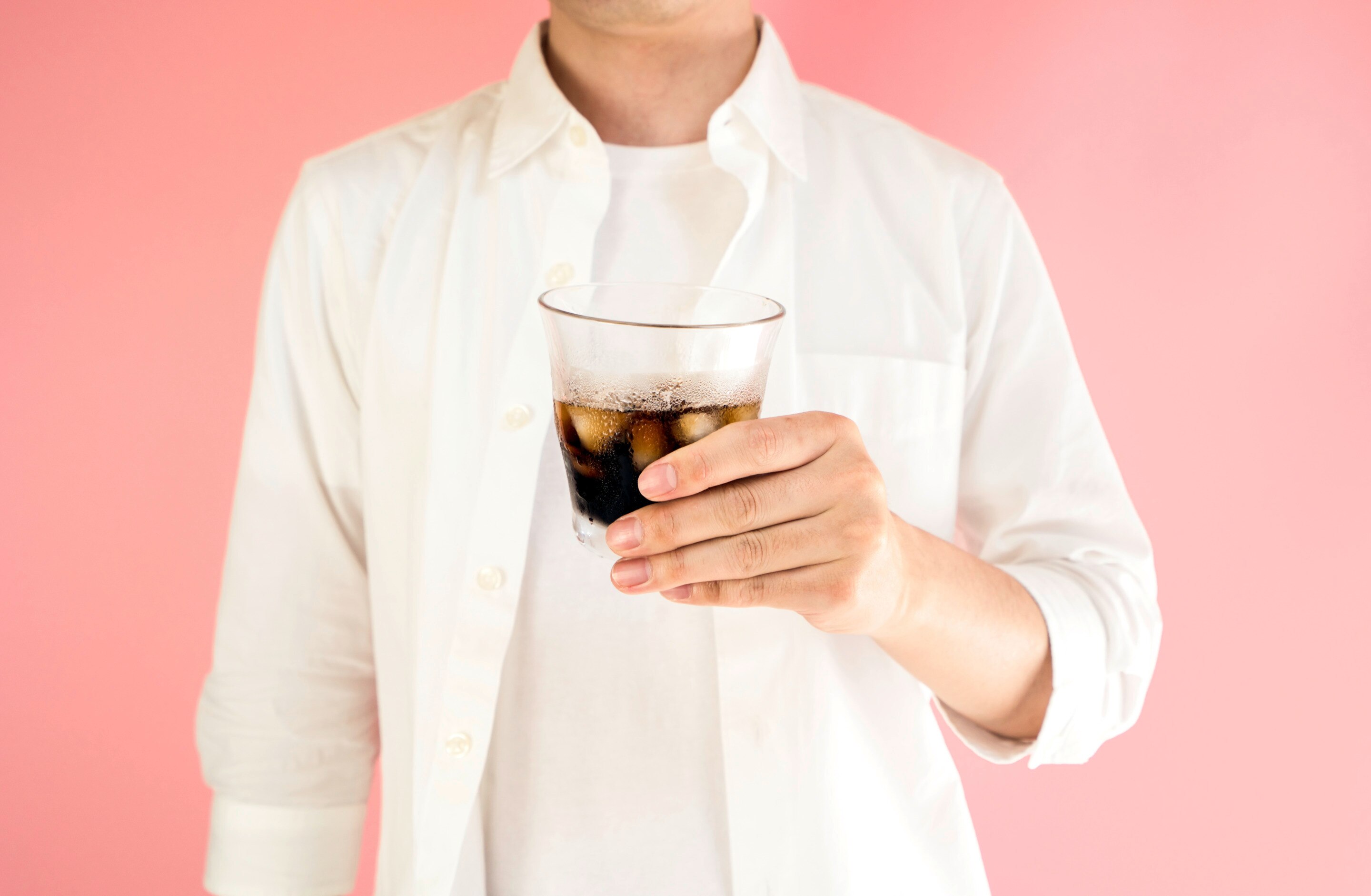 Man in white holding iced coffee 