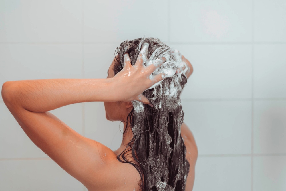 Woman shampooing her long hair in the shower.
