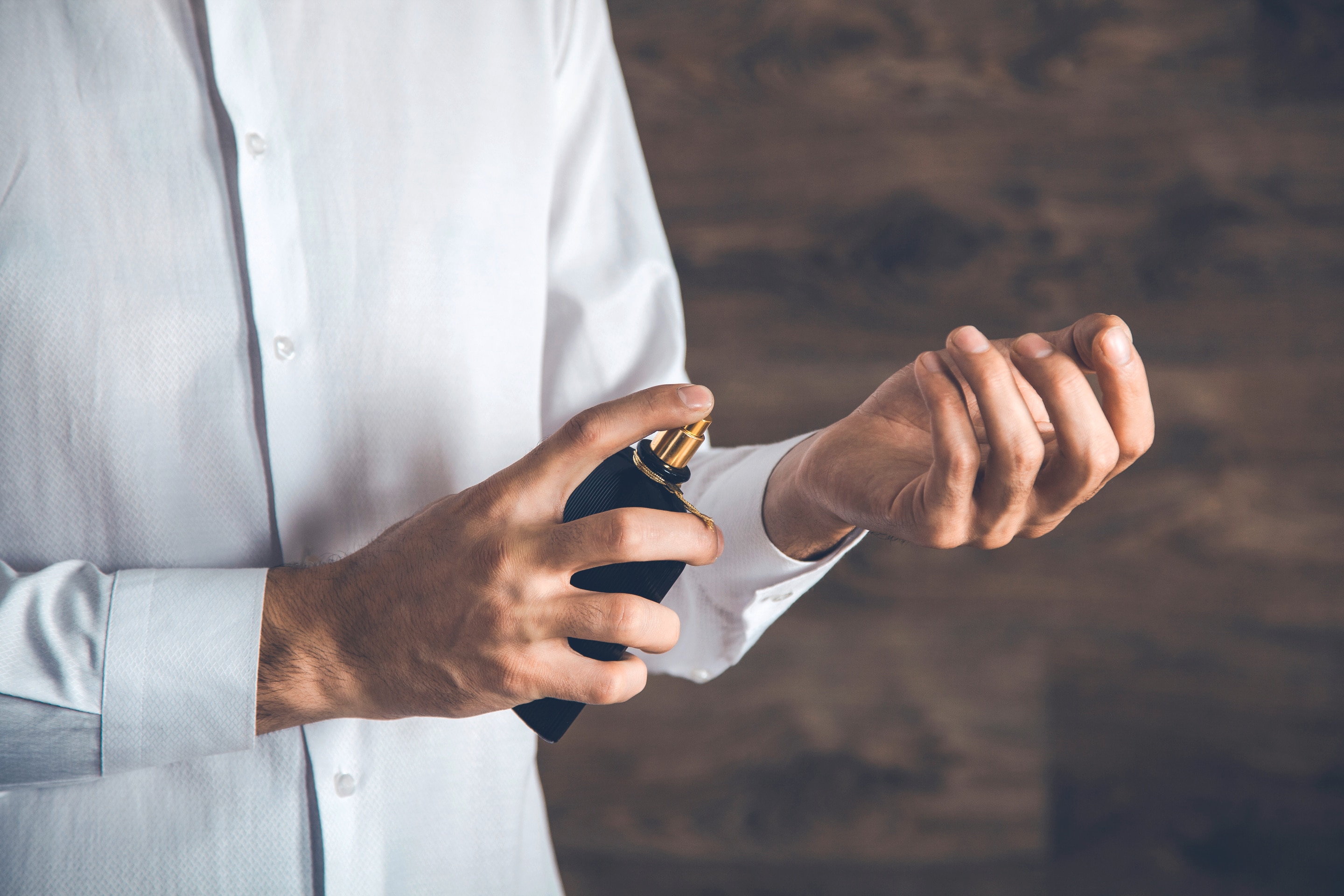 Close up on man spraying cologne on his wrist