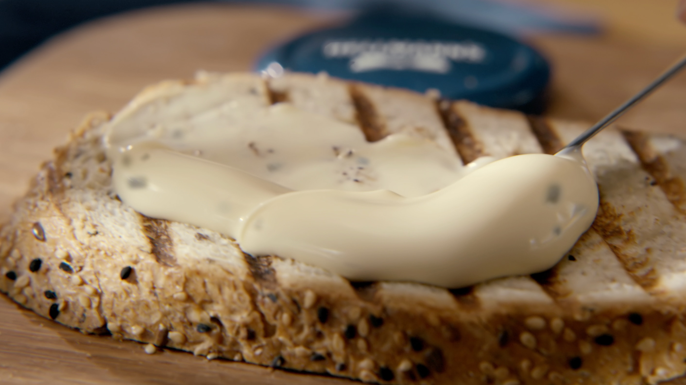 A creamy layer of mayonnaise is spread on a toasted bread