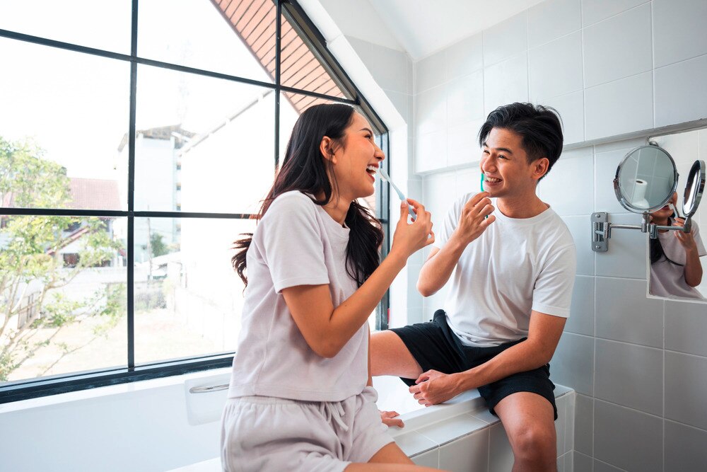Woman and man brushing their teeth together in a bathroom.