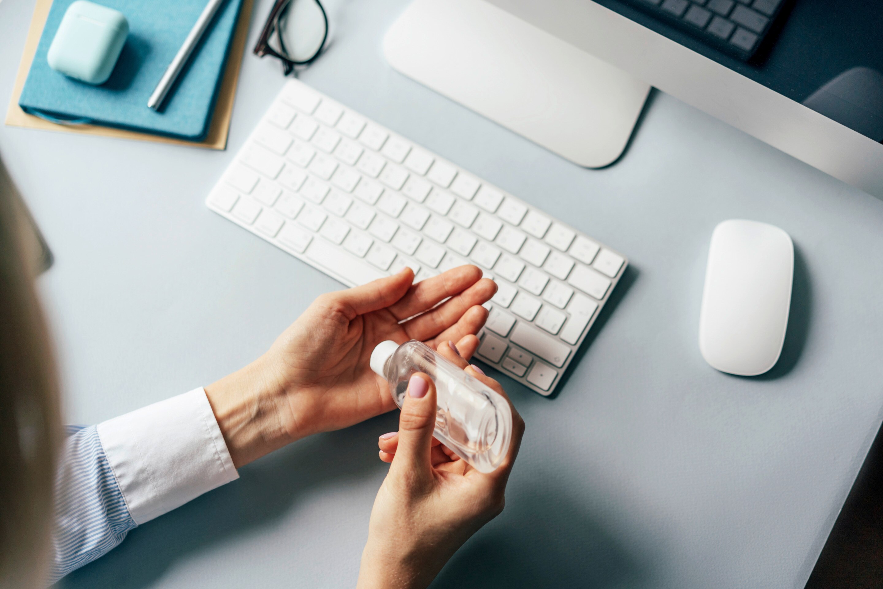 Hands disinfecting keyboard with hand sanitizer