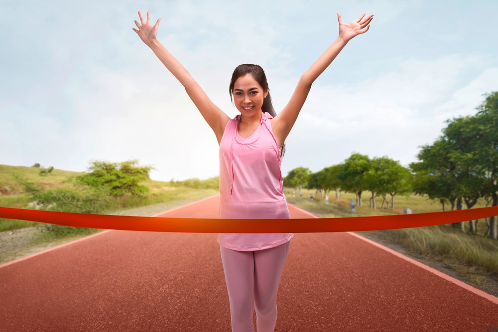Asian runner wearing a loose pink sports top and pink leggings. 