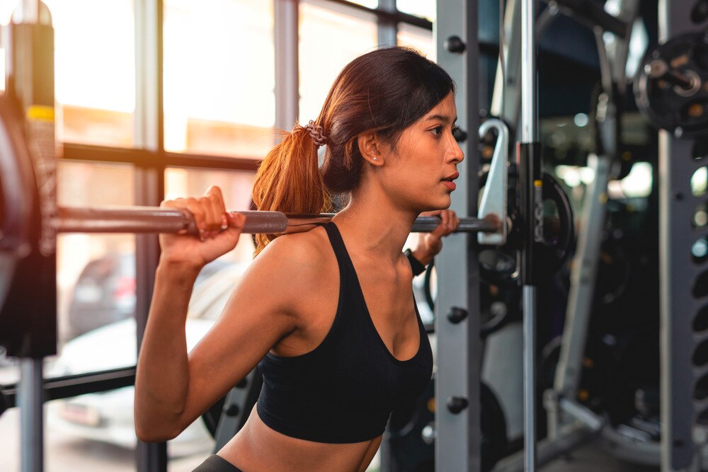 Woman doing weighted squat at the gym.
