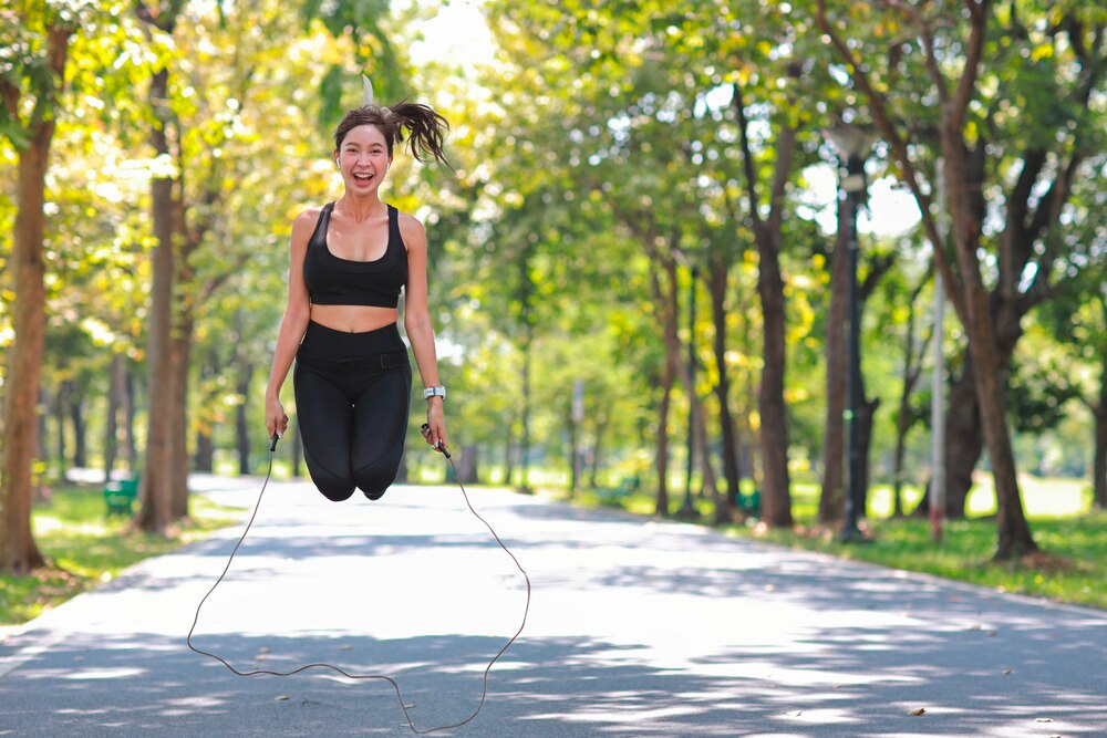 A portrait of woman jumping rope outdoors.