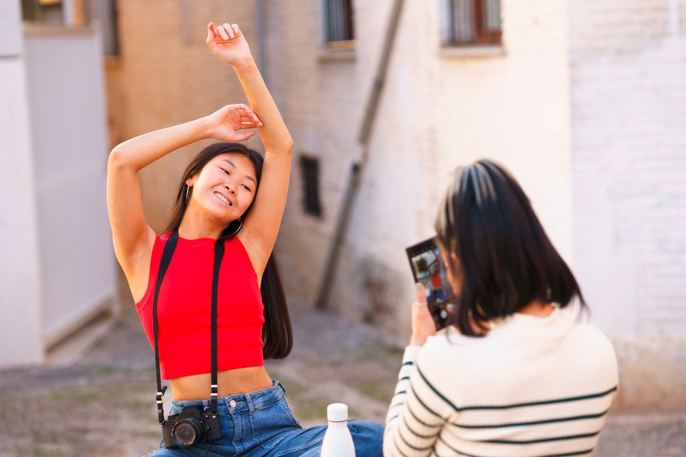 Woman tourist in red crop top posing with her arms raised.