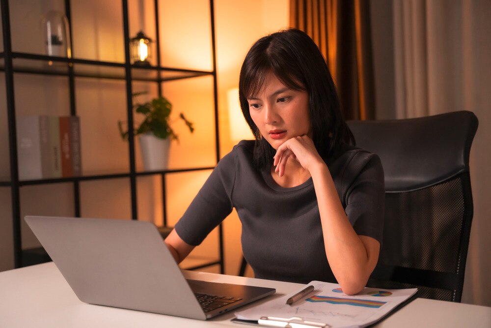 Asian woman with concerned face looking at laptop in the office.
