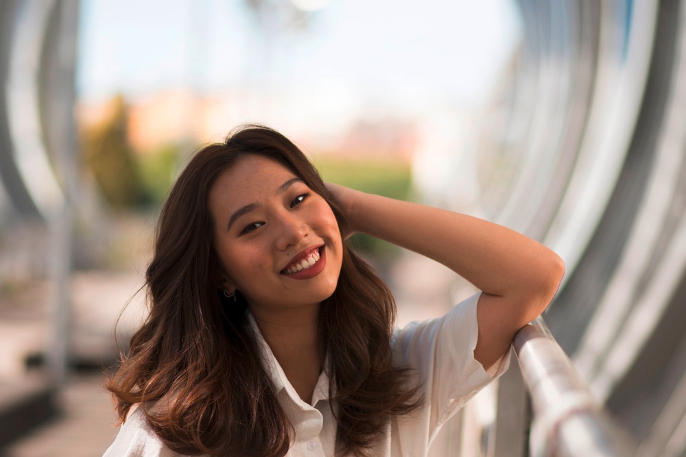 Woman with long brown hair smiling to the camera.