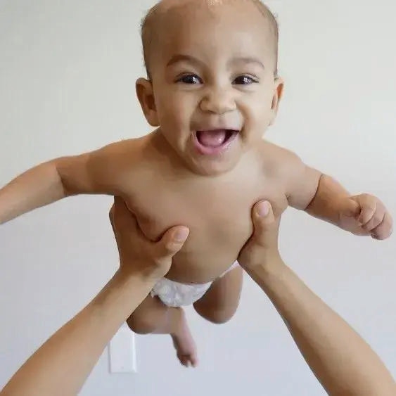 Bebe sorrindo sendo segurado no alto