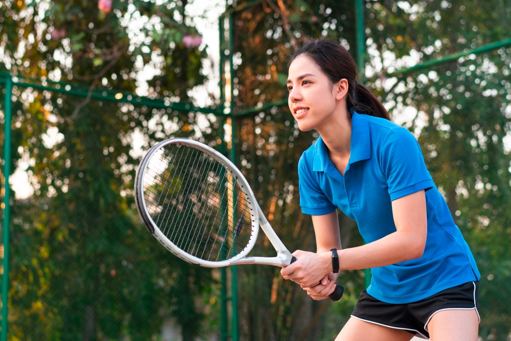 Woman in blue polo shirt playing tennis.