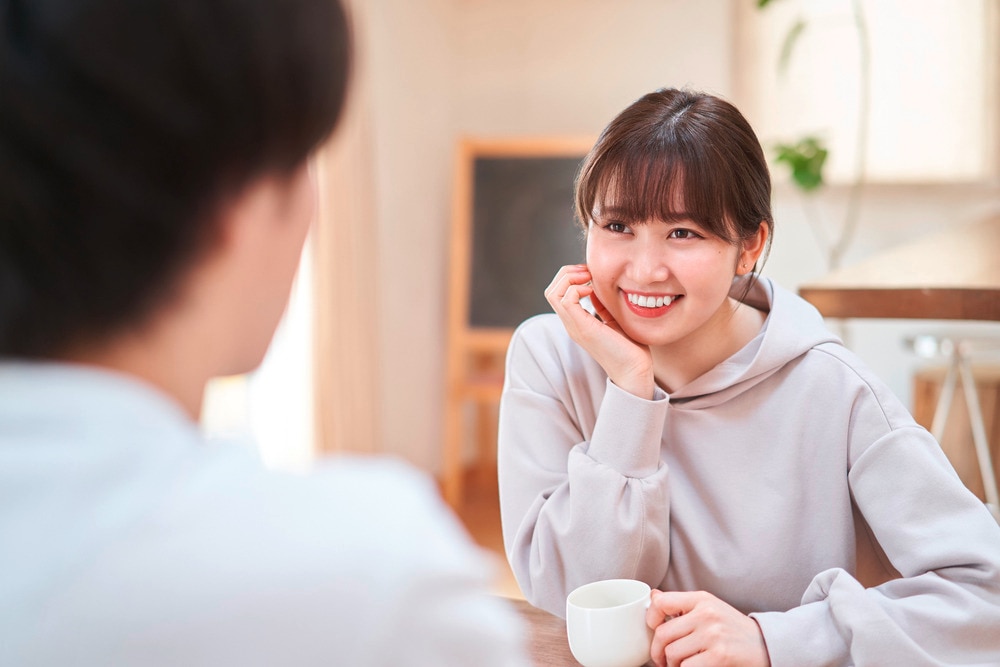 Woman with ponytail and bangs staring happily at her male friend.