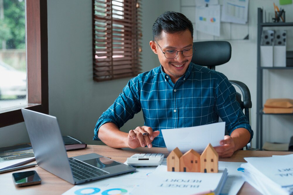 Asian man crunching numbers on a laptop.