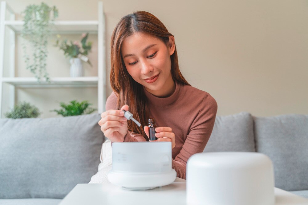 Woman dropping essential oil in a bowl.
