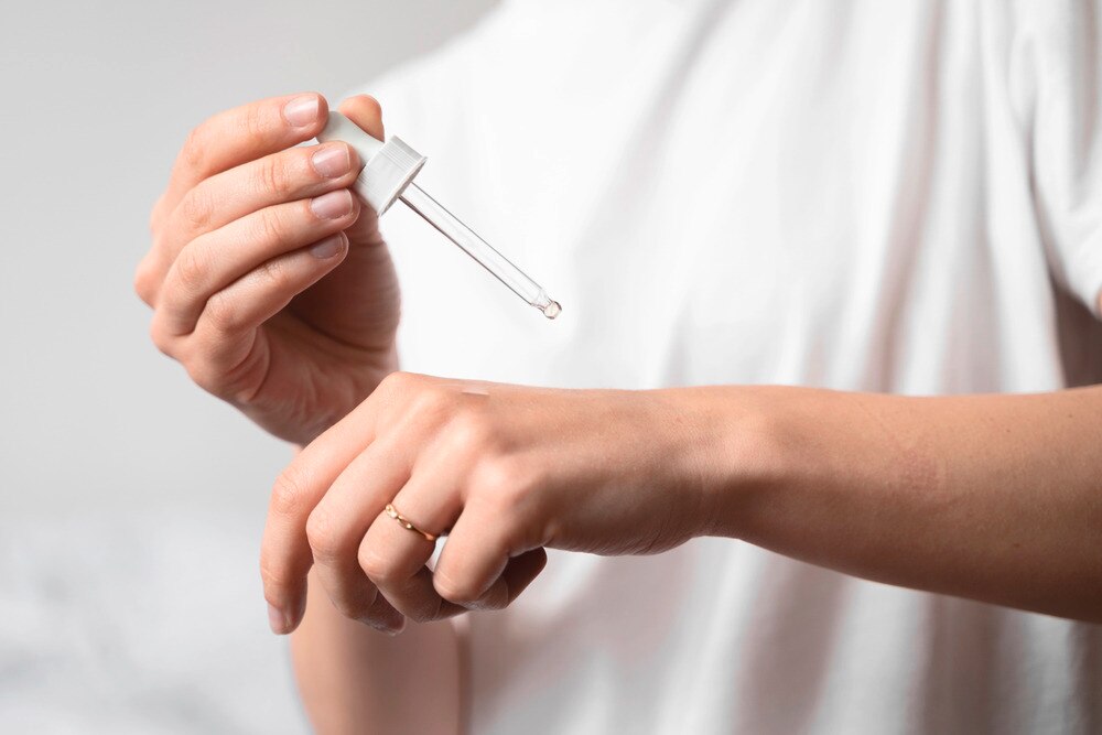 Woman testing the temperature of essential oil on her hand.