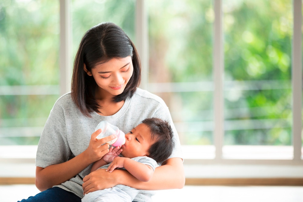 Mother bottle feeding her baby with milk formula.