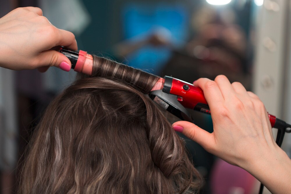 Woman using a curling wand on her hair.