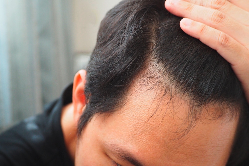 Asian man slicks back hair with hand