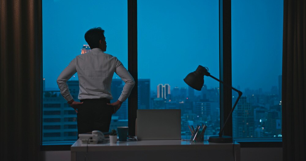 Asian businessman contemplating by an office window.
