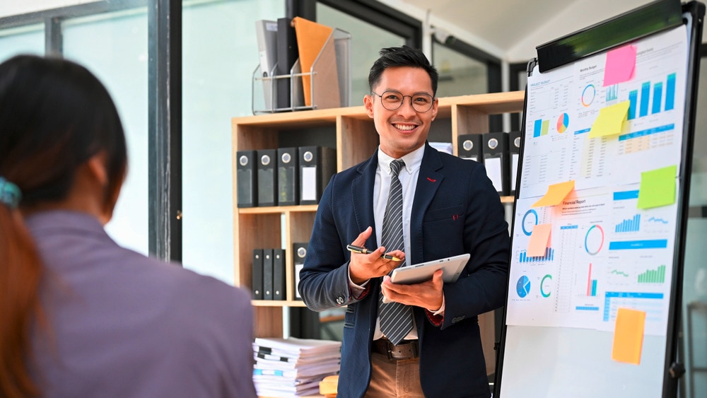 Asian man presenting data in a meeting room.