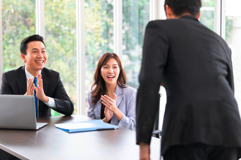 Male and female bosses applauding a male worker for his promotion.