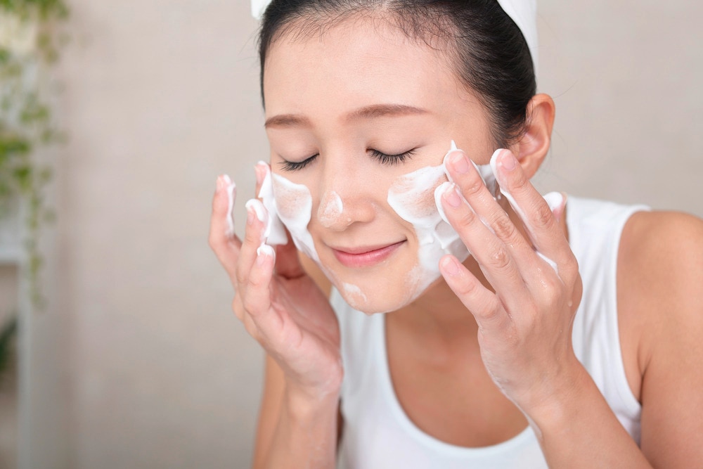 Woman washing her face with foaming cleanser.