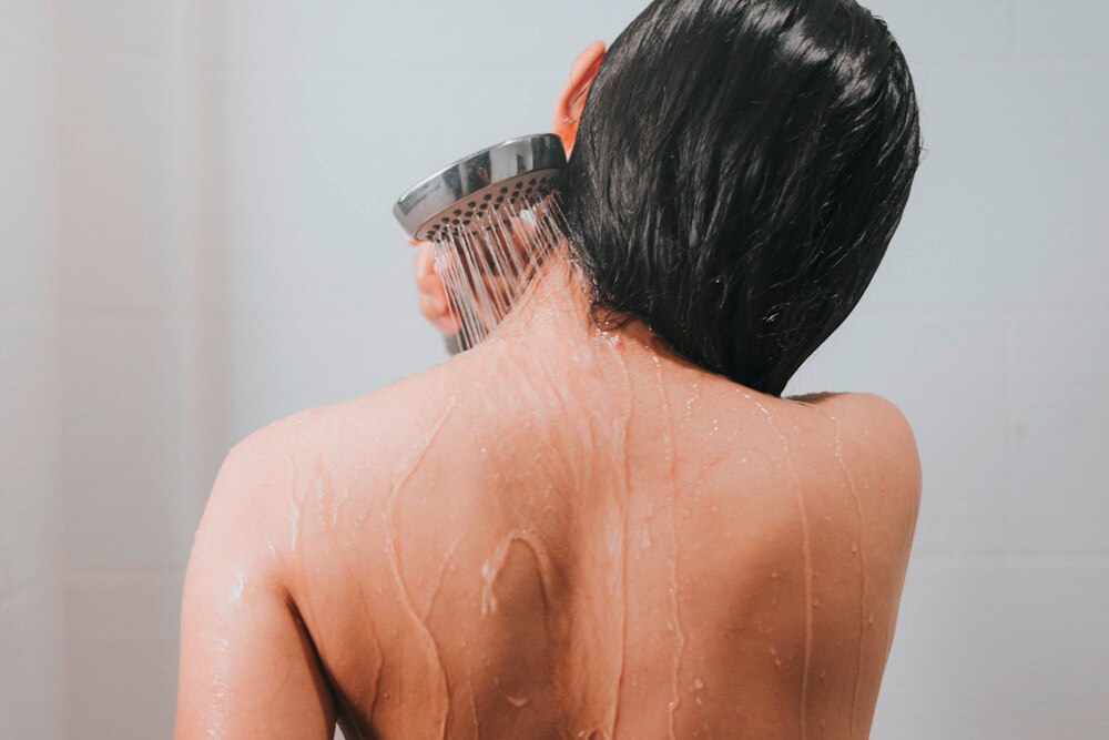 Woman washing her back in the shower.