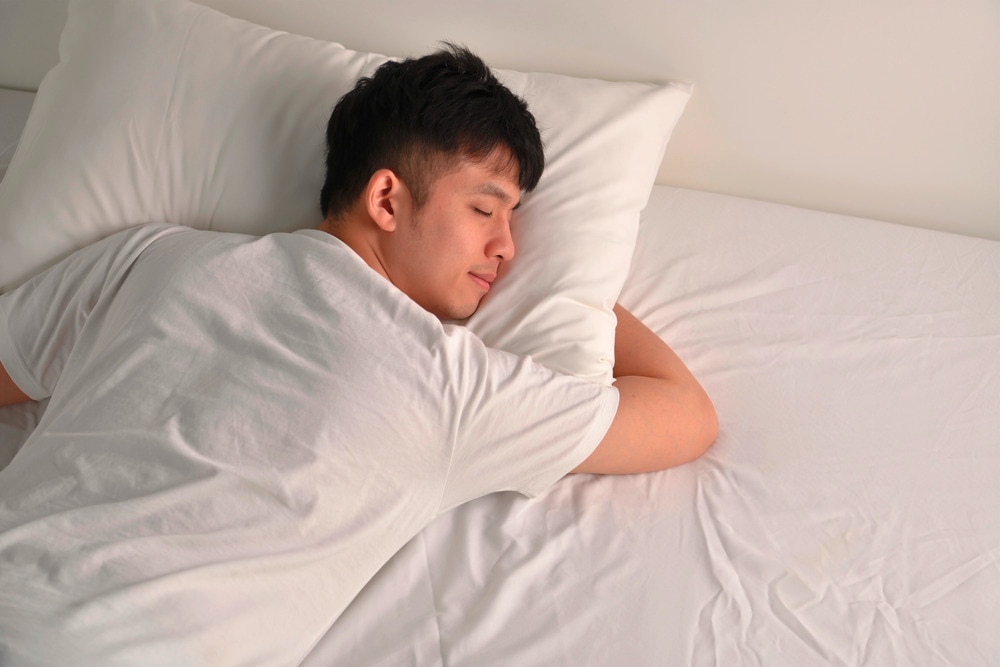 Asian man sleeping on bed.