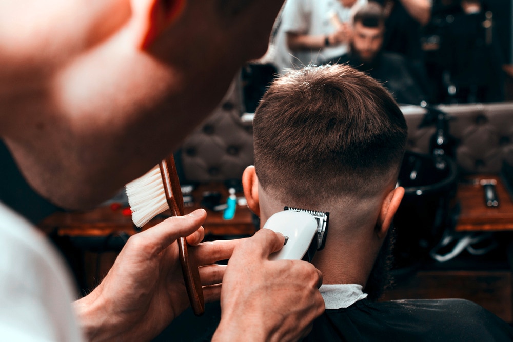 Barber using clippers to create a fade on a man’s head