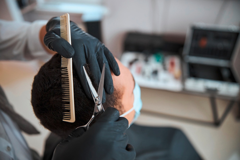 Barber cutting a man’s hair using a pair of scissors and a comb.