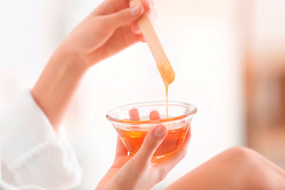 Woman holding a glass bowl full of wax.
