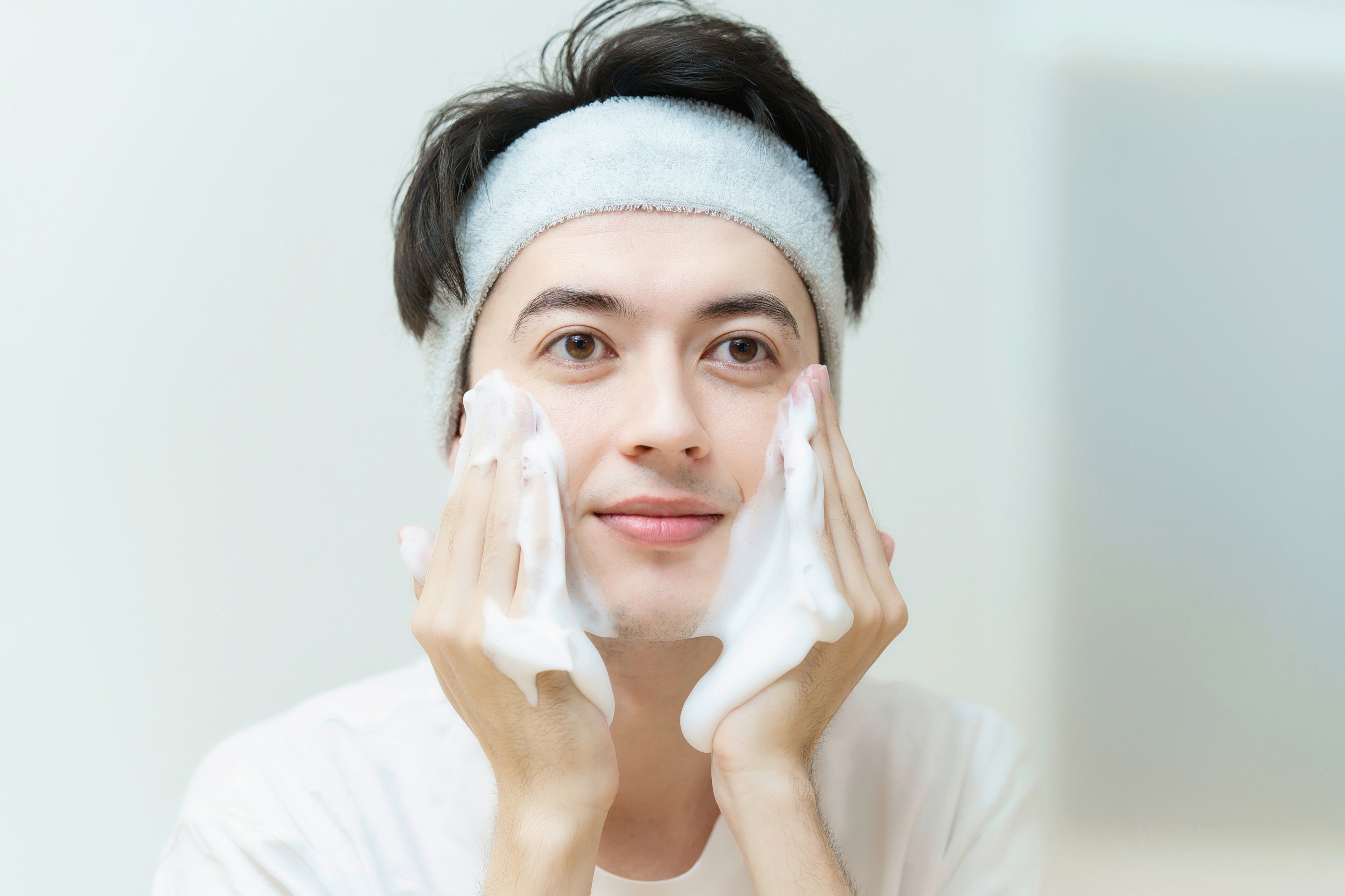 Asian man lathering soap on cheeks