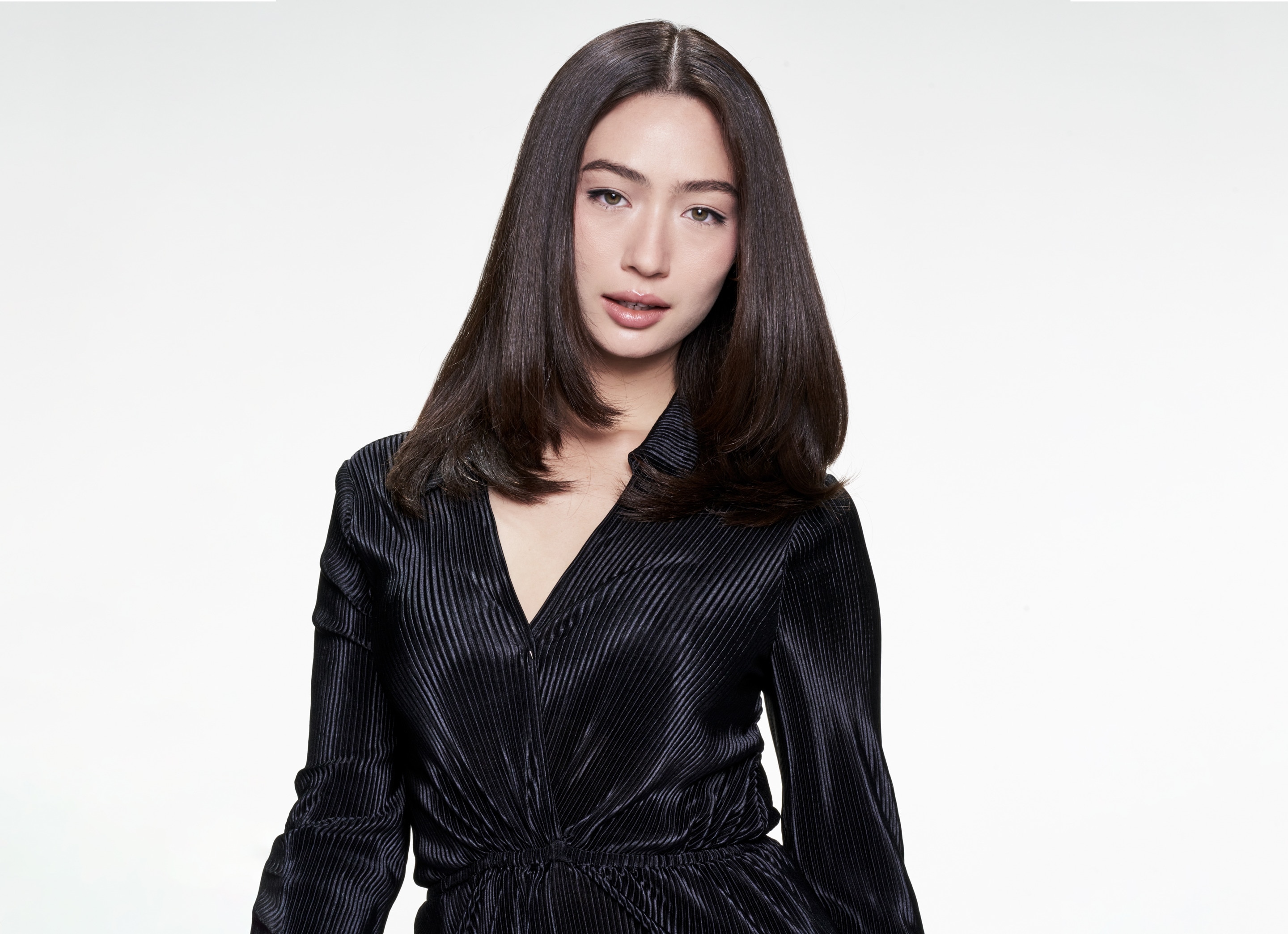 A model with part of her blonde hair up in hair clips and a stylist applying mousse to it