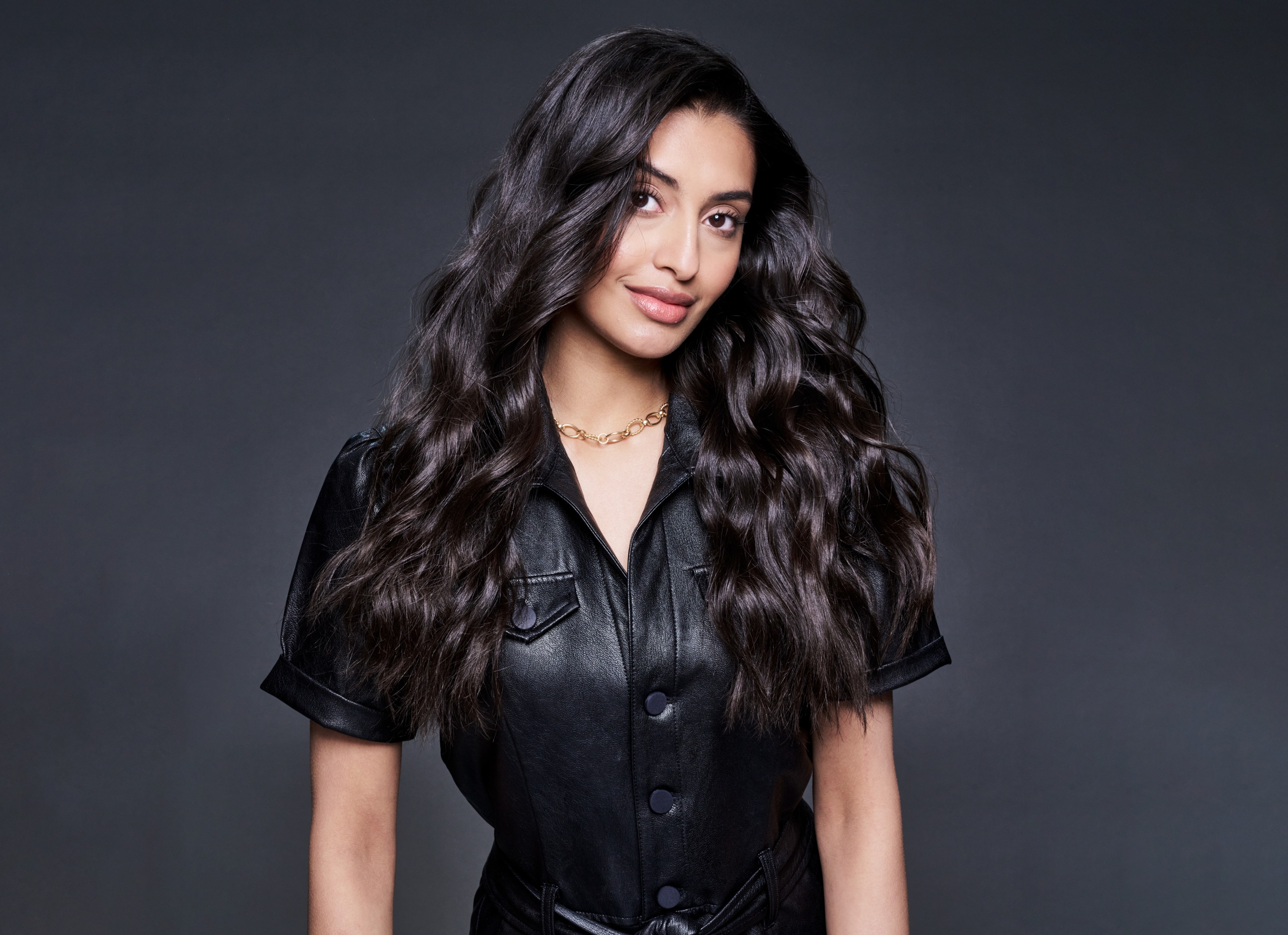 A model with part of her blonde hair up in hair clips and a stylist applying mousse to it