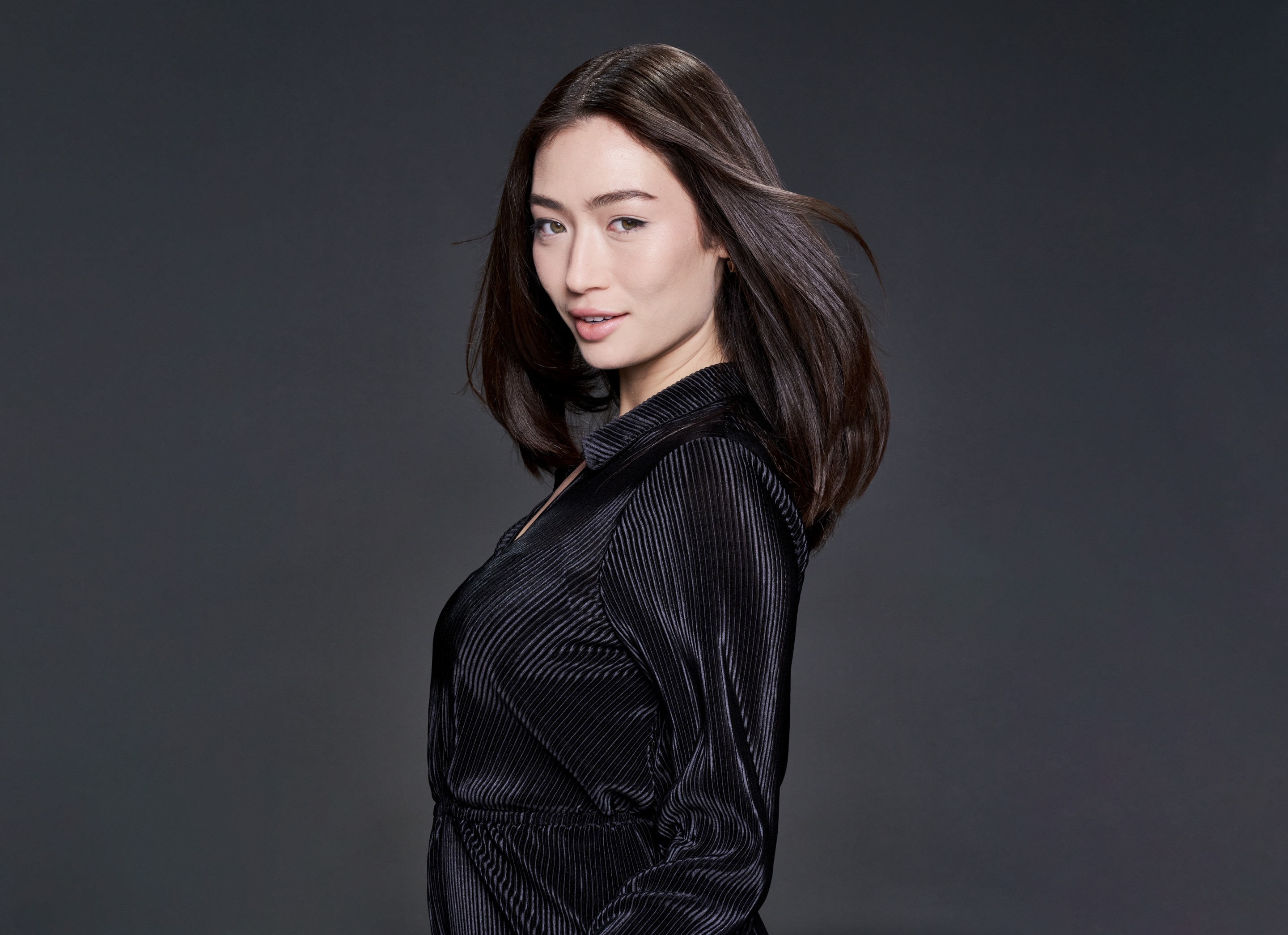 A model with part of her blonde hair up in hair clips and a stylist applying mousse to it