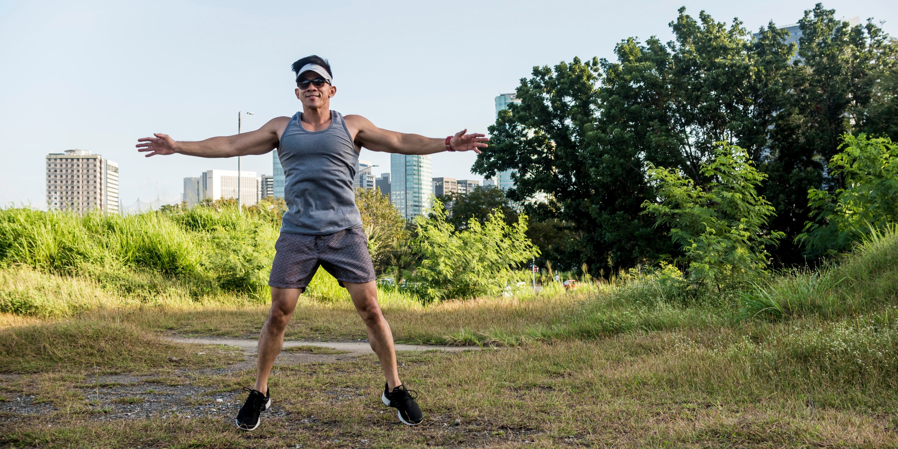 Asian man outdoors doing jumping jacks