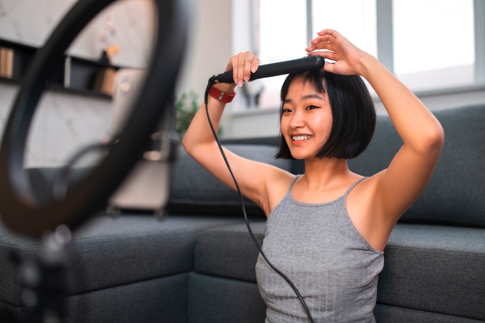 Asian vlogger with short hair styling her bangs.