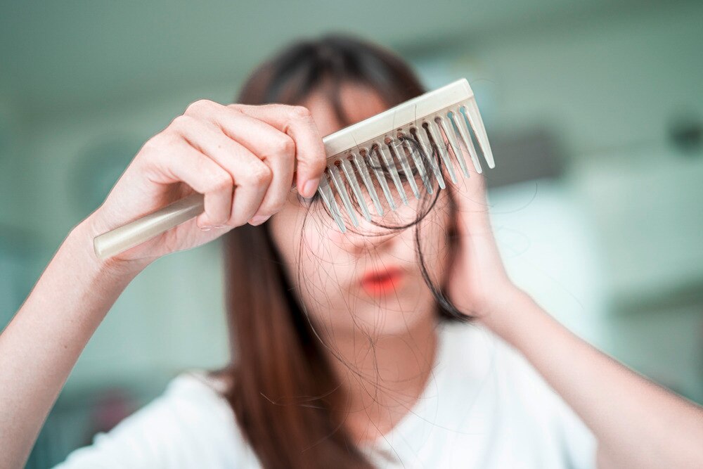 Closeup of a woman’s comb with strands of hair stuck in it.