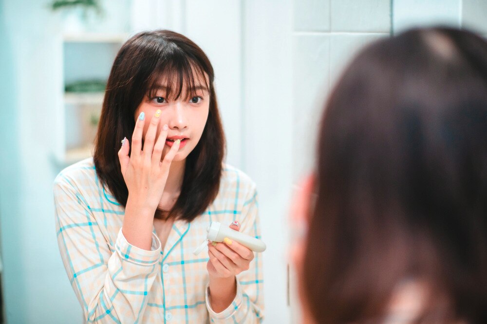 Woman applying face cream to her cheek.