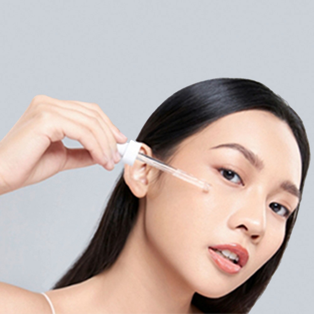 A beautiful woman putting niacinamide onto her skin 